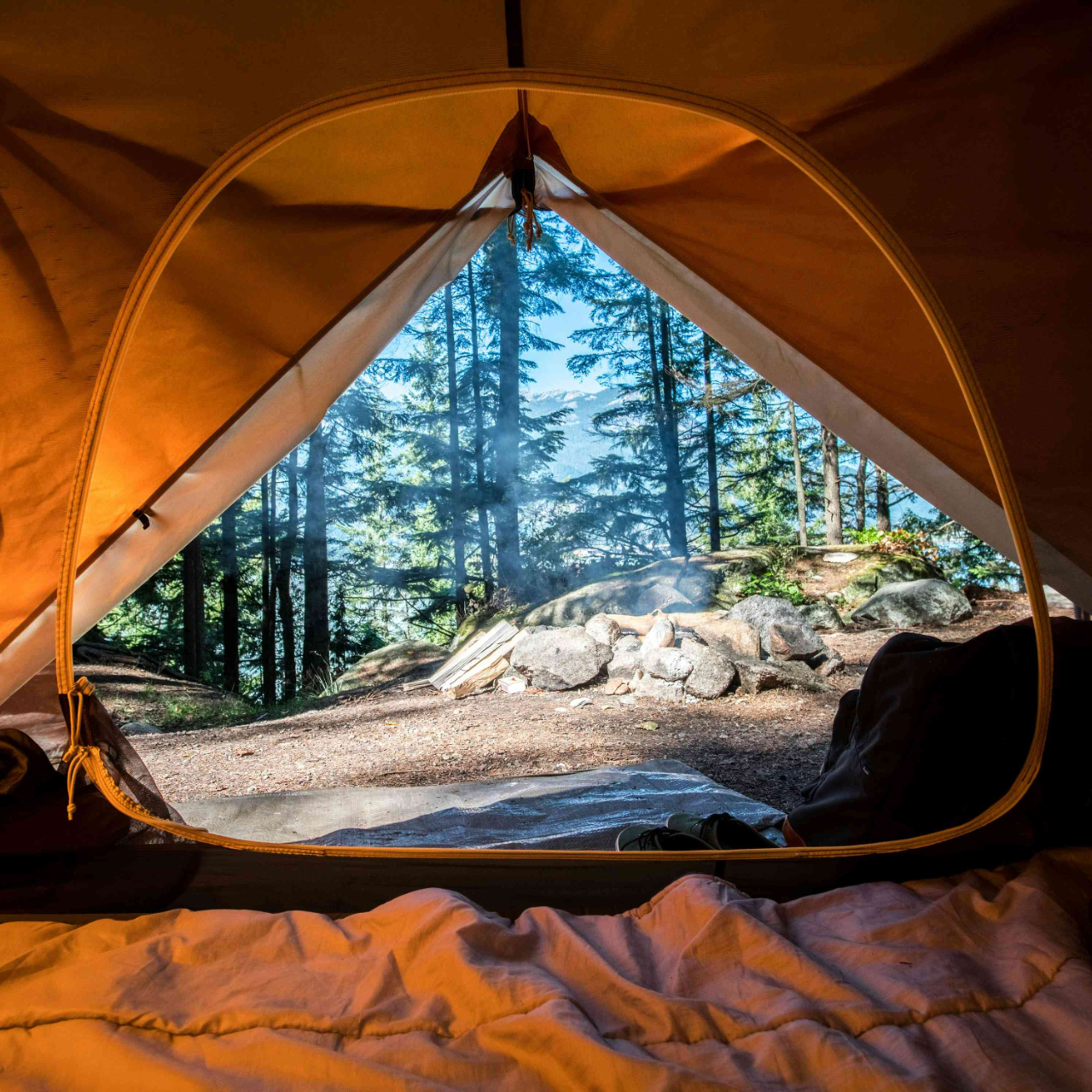 Olive camping tent and portable lantern at a lakeside campsite